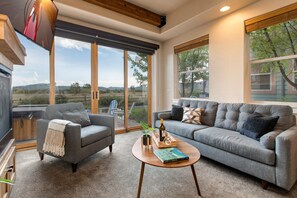 Living Room with plush couch, armchair, gas fireplace, 50" TV, and private hot tub patio access