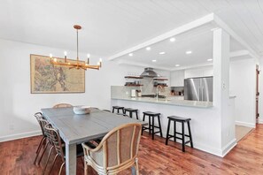 View of the dining area and fully-equipped kitchen with 4 breakfast bar stools