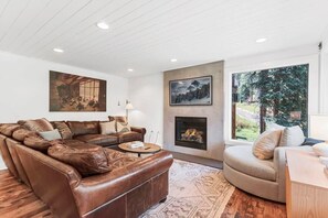 Relax in the family room with a luxurious sectional leather couch, a comfortable round sofa, indoor gas fireplace, and a flat-screen TV.