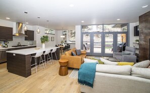 Open and social kitchen with breakfast bar for three, living room and seated dining for eight