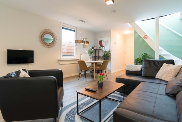Bright and spacious living area with modern decor, comfortable seating, and dining table – ideal for relaxing after a day in Alkmaar.