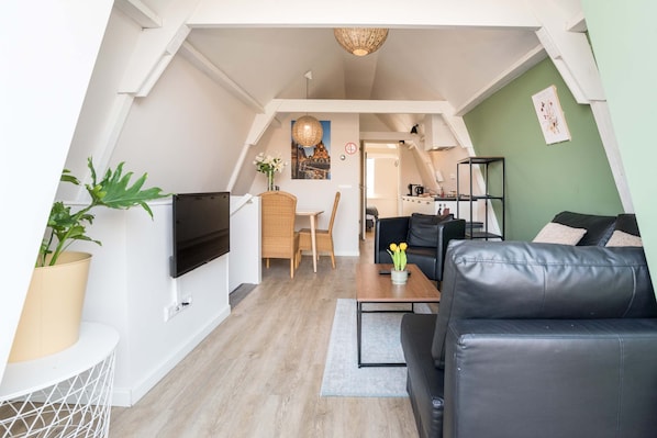 Bright and cozy living area on the second floor, featuring stylish seating, a flat-screen TV, and a welcoming dining space.