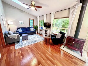 Main Cottage living room open concept two huge panoramic mirror reflective windows wooded views skylight vaulted ceilings tons of natural light 