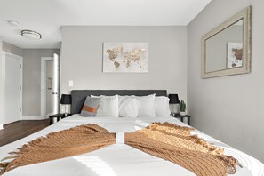 King size bed in master bedroom with soft pillows sheets and comforters. 