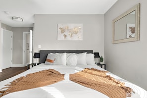 King size bed in master bedroom with soft pillows sheets and comforters. 