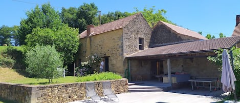 Bâtisse de la maison girafe et salon de jardin abrité donnant sur la piscine. 