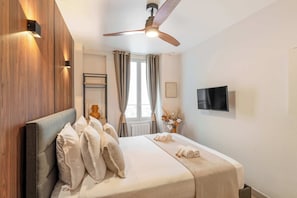 A comfy sleeping couch with flat screen TV and ceiling fan.