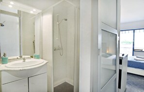Das Badezimmer mit Duschkabine, Waschbecken mit Spiegel und Unterschrank, WC und Fön
