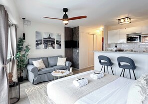 Spacious studio with a queen-size bed, ceiling fan, and ample storage