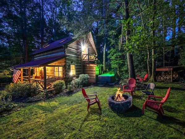 Cabin at dusk with fire blazing and Jacuzzi lite up!