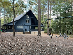 Newly painted outside view including play set, firepit and outdoor games.