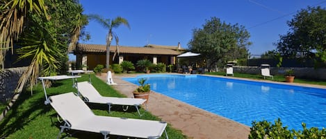 La grande piscine, la pelouse bien entretenue et la villa avec son portique.