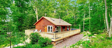 Summer view of the Main Cottage. Apple tree out front & front lounge chairs, 1k wrap around deck. Back deck dining table & lounge couch, propane fireplace (seasonal outdoor furniture May-Oct)