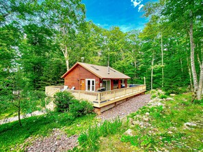 Summer view of the Main Cottage. Apple tree out front & front lounge chairs, 1k wrap around deck. Back deck dining table & lounge couch, propane fireplace (seasonal outdoor furniture May-Oct)