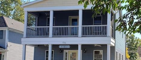 The front of the house features an open porch and screened-in balcony upstairs.