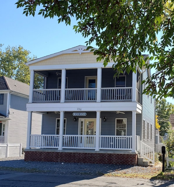 The front of the house features an open porch and screened-in balcony upstairs.