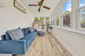 Sun room with fan, sofa, egg chair and big windows.
