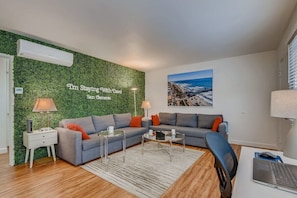 Sophisticated living room design with two sofas that open to full size beds, 50” 4K TV, work desk station, beautiful decor, and so much more!