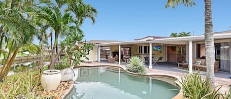 Beautiful pool area overlooking the water with lounge chairs in the pool. 