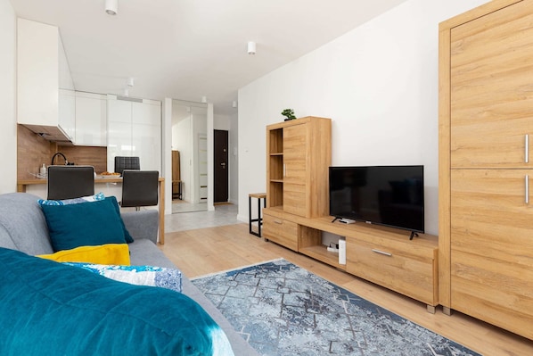 A spacious living room with a light gray sofa, a wooden TV stand, and modern decor, creating a cozy and functional space.
