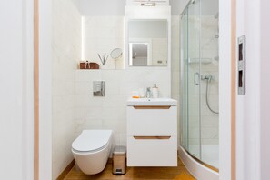 A sleek bathroom with a walk-in shower, white tiles, and natural wood accents for a contemporary look.