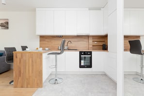 A modern kitchen with white cabinets, wooden accents, and built-in appliances, ideal for cooking and dining.