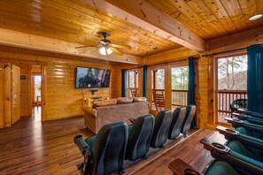 The lower level theatre room equipped with theatre style chair, tv and sofa.