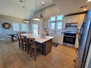 Kitchen and Diningroom - Well-appointed kitchen featuring quartz, white and stainless appliances, and a sizeable island, ideal for preparing home-cooked meals.