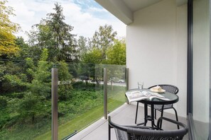 A balcony with a small table and chairs, overlooking a lush green yard for outdoor relaxation.
