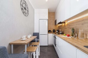 A dining area with a modern table, comfortable chairs, and a wall clock adding a decorative touch.
