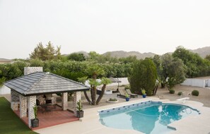 Aerial view of the ramada, pool, and patio with firepit.