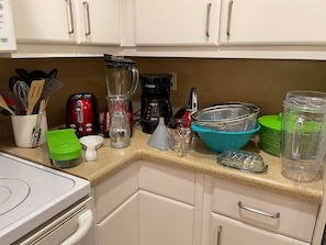 These are some of the larger items in the kitchen.The stove is to the left, and the refrigerator is on the right.There are steel bowls in the back behind the colanders.