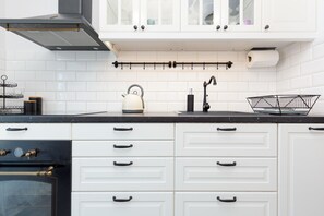 A modern kitchen area with a white tiled backsplash, black countertop, and open shelving for a contemporary feel.