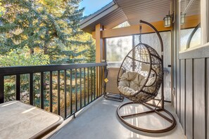 Private Balcony backing onto a treed lot with reclining chairs, table and swing