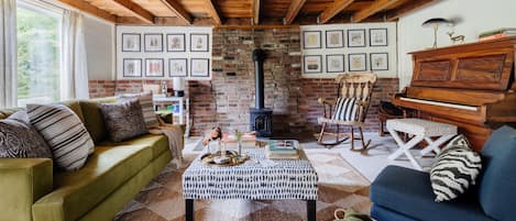 Den with wood burning stove and piano.