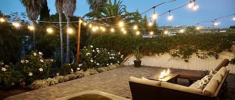 Spa, fire pit, string lights, and outdoor seating on the main backyard level