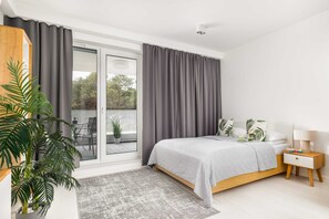 A cozy sleeping nook integrated into the studio space, with a double bed and soft, neutral bedding.