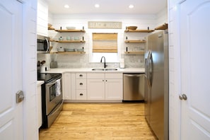 - Channel your inner chef in this fully equippped kitchen with open shelving and fresh style - Stocked with essentials, stainless appliances, and a beachy vibe up top - Welcoming space for morning brews or full family feasts with ease