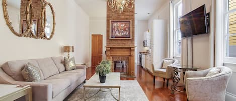 Living area w/kitchen past decorative fireplace and bathroom behind wood door