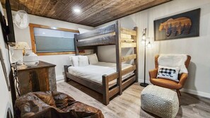 The second bedroom is a well-decorated space with a twin-over-queen bunk bed and a plush reading chair.