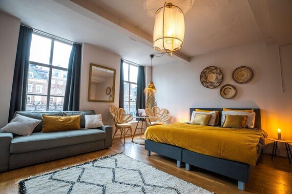 Room 1 – Our spacious yellow suite with a view
A bright and open room with warm yellow tones, a comfy sofa and big windows overlooking the square.