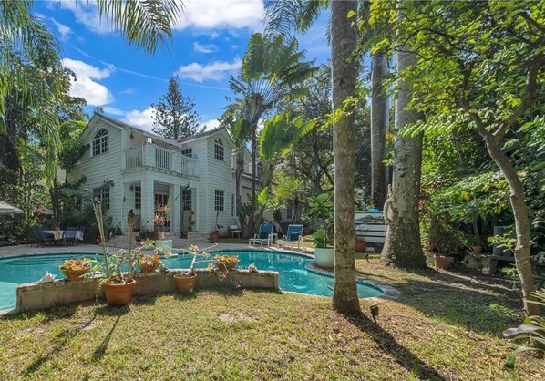 View of home from backyard pool area filled with palm trees