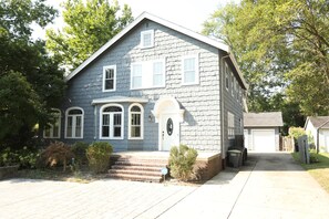 Front of House from front two parking spaces showing detached garage, trash and recycling containers