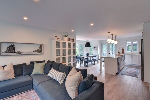 Spacious living area featuring a black sofa, elegant wall art, and crisp white walls—blending comfort with modern style.