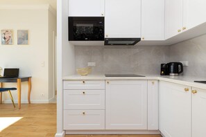A compact kitchen with white cabinets, a black countertop, and all essential appliances.

