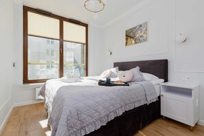 A stylish bedroom with a comfortable double bed, soft gray bedding, and a modern aesthetic.

