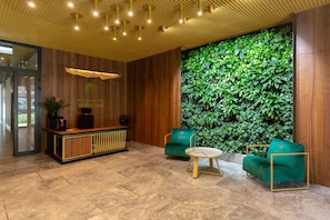 A modern lobby with a vibrant green wall and comfortable seating, creating a welcoming atmosphere.
