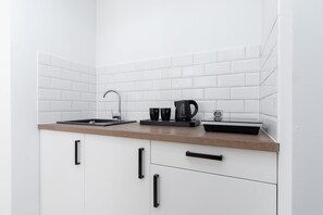 A minimalist kitchenette featuring a kettle and compact appliances for convenience.


