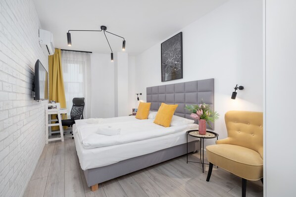 A cozy bedroom with a gray upholstered bed, vibrant yellow accents, and a modern armchair.

