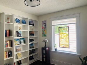 Bookcase along side a big window, bright and vibrant. 